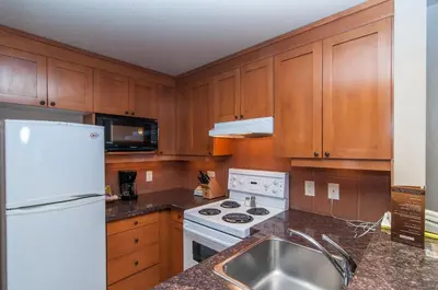 a kitchen with wooden cabinets and a white refrigerator at The Hidden Ridge Resort in Banff