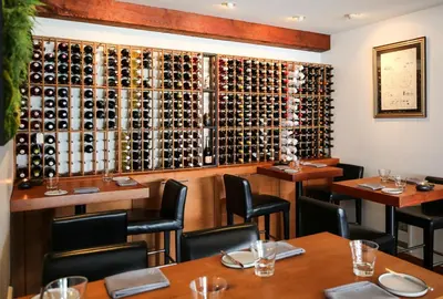 a restaurant with tables and a wall of wine bottles at Pluvio restaurant and rooms in Ucluelet
