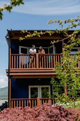 two people standing on a balcony of a house at Pluvio restaurant and rooms in Ucluelet