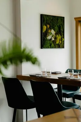a table with chairs and a picture on the wall at Pluvio restaurant and rooms in Ucluelet