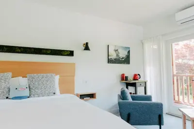 a bedroom with a bed and two blue chairs at Pluvio restaurant and rooms in Ucluelet