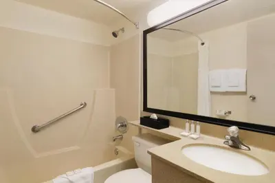 a bathroom with a sink and a toilet and a mirror at Travelodge by Wyndham Edmonton South in Edmonton