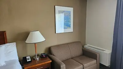 a room with a bed and a chair and a lamp at Comfort Inn in Chilliwack