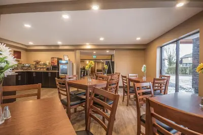 a restaurant with wooden tables and chairs and a kitchen at Comfort Inn in Chilliwack