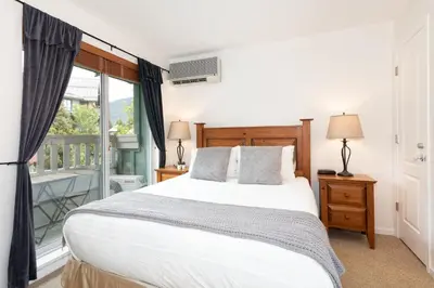 a bedroom with a large bed and a balcony at Bear Lodge (Town Plaza) in Whistler