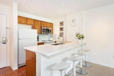 a kitchen with a white counter and stools at Bear Lodge (Town Plaza) in Whistler