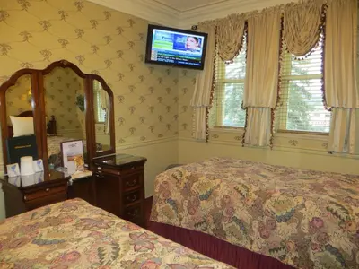 a bedroom with two beds and a television on the wall at Athabasca Hotel in Jasper
