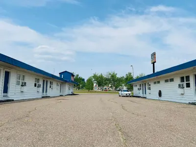 a row of white buildings with a car parked between them at Shannon Motel in Fort Nelson