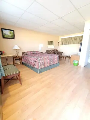 a large bedroom with a bed and a wooden floor at Shannon Motel in Fort Nelson