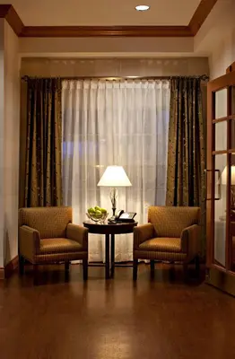 a living room with two chairs and a table and a window at Country Inn & Suites by Radisson, Calgary-Northeast in Calgary