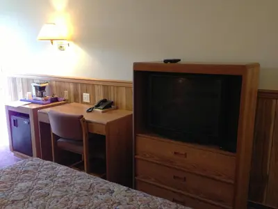 a hotel room with a television and a desk and a bed at Rainbow Motor Inn in Chilliwack