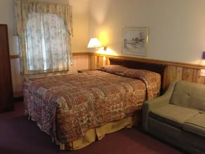 a hotel room with a bed and a chair at Rainbow Motor Inn in Chilliwack