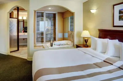 a hotel room with a large bed and a bathroom at Chateau Nova Kingsway in Edmonton