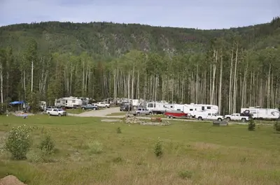 a group of rvs parked in a field in a forest at Williston Lake Resort in Hudson Hope