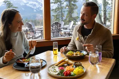 a man and woman sitting at a table eating food at The Juniper Hotel & Bistro in Banff