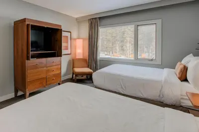 a hotel room with two beds and a television at The Juniper Hotel & Bistro in Banff