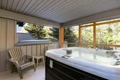 a hot tub on a screened in porch with a chair at Glaciers Reach by Allseason Vacation Rentals in Whistler