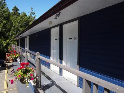 a blue house with a porch with a door and flowers at Tofino Motel Harbourview in Tofino
