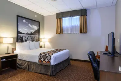 a hotel room with a bed and a flat screen tv at Super 8 by Wyndham Cochrane in Cochrane