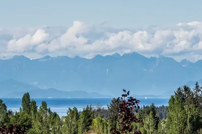 a view of the mountains and the water with trees at Vancouver Island Residences in Nanaimo