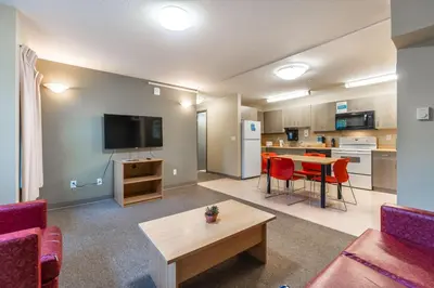 a living room with a couch and a table and a kitchen at Vancouver Island Residences in Nanaimo