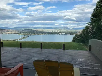 a view of a lake from a patio with chairs at Lake and Bridge View Vacation Home in West Kelowna