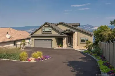 a house with a driveway in front of it at Lake and Bridge View Vacation Home in West Kelowna