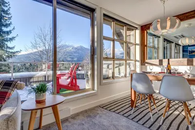 a kitchen with a table and chairs and a large window at THE LOOKOUT PENTHOUSE // a luxe suite in Whistler in Whistler