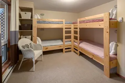 a bunk bed room with two bunk beds and a chair at Falcon Cabin in Fairmont Hot Springs