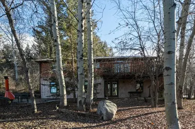 a log cabin in the woods with a rock at Creekside Cabin in Fairmont Hot Springs