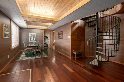 a living room with a spiral staircase and a table at Creekside Cabin in Fairmont Hot Springs