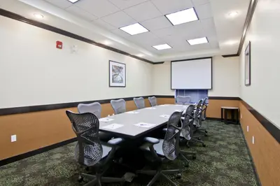a conference room with a table and chairs and a whiteboard at Wingate by Wyndham Fort Saskatchewan in Fort Saskatchewan