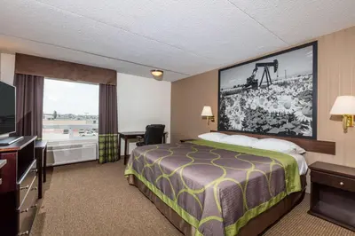 a hotel room with a bed and a flat screen tv at Super 8 by Wyndham Edson in Edson