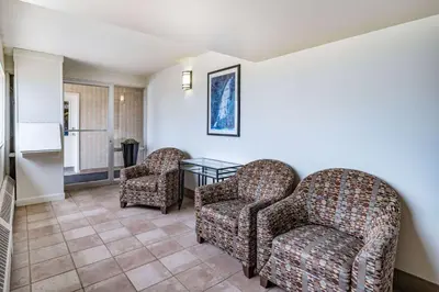 a living room with two chairs and a glass table at Travelodge by Wyndham Fort St John in Fort Saint John