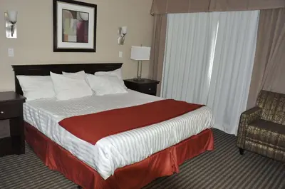 a hotel room with a large bed and a chair at Ramada by Wyndham Abbotsford in Abbotsford