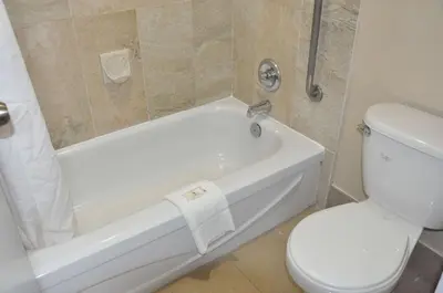 a bathroom with a white tub and a toilet at Ramada by Wyndham Abbotsford in Abbotsford