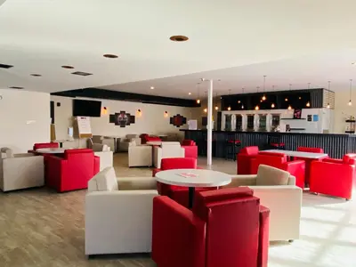 a restaurant with red and white chairs and tables at Ramada by Wyndham Whitecourt in Whitecourt