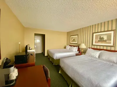 a hotel room with two beds and a television at Ramada by Wyndham Whitecourt in Whitecourt