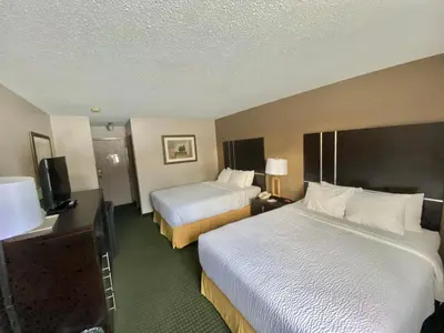 a hotel room with two beds and a television at Ramada by Wyndham Whitecourt in Whitecourt