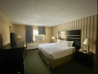 a hotel room with a bed and a television at Ramada by Wyndham Whitecourt in Whitecourt