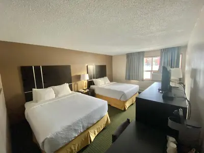a hotel room with two beds and a television at Ramada by Wyndham Whitecourt in Whitecourt