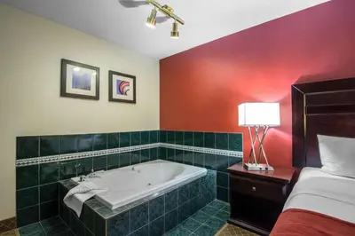 a bathroom with a bath tub next to a bed at Comfort Inn & Suites Airport South in Calgary