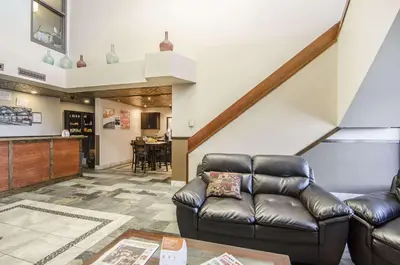 a living room with a leather couch and a staircase at Econo Lodge Lloydminster in Lloydminster