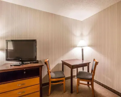 a hotel room with a desk with a television and two chairs at Quality Inn & Conference Centre in Red Deer
