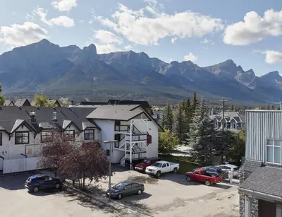 a town with cars parked in a parking lot with mountains at Sundance Suite - Beautiful Condo With Open Pool And Hot Tub in Canmore