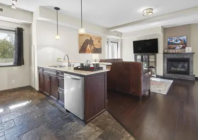 a kitchen with a sink and a living room at Sundance Suite - Beautiful Condo With Open Pool And Hot Tub in Canmore