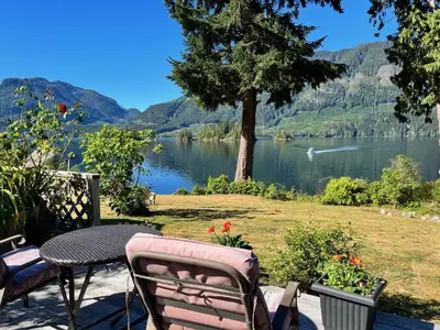 a patio with a table and chairs and a view of a lake at Frigon Suite -Waterfront in Port Alice