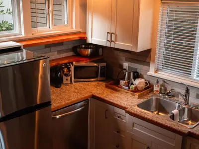 a kitchen with a stainless steel refrigerator and a sink at Mid-Island Getaway - Sunken Hot Tub & Deck - Close to Beach - Modern in Nanaimo