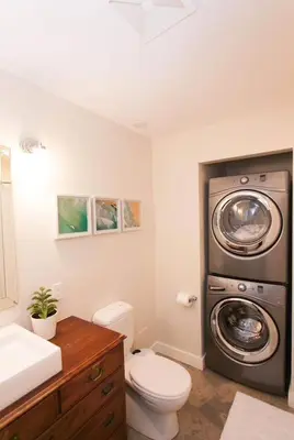 a bathroom with a toilet and a washing machine at Mid-Island Getaway - Sunken Hot Tub & Deck - Close to Beach - Modern in Nanaimo