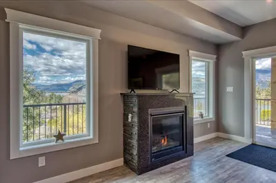 a fireplace in a living room with windows at Semi-Lakefront Luxury Retreat In Blind Bay, Bc Cottage in Blind Bay